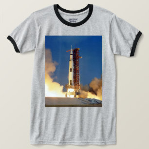 Aarde schudt terwijl Saturnus V de hemel verlicht T-shirt