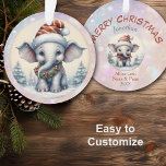 Adorable bébé éléphant petit-enfant<br><div class="desc">Voici un joli ornement de Noël pour ce petit-fils ou petite-fille spécial ! Un bébé éléphant blanc porte un casquette du Père Noël rayé et un foulard à couronne sur le devant. Derrière lui se trouve un paysage enneigé de pins. L'image est placée sur un arrière - plan bokeh rose...</div>