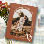 Arche photo moderne Mariage en terre cuite<br><div class="desc">Un élégant calendrier wedding planner en spirale présente votre photo dans une disposition unique voûtée sur un arrière - plan en terre cuite, vos noms joints avec une grande ampersande blanche en bas et votre date mariage voûtée en haut. Changez la couleur du livre sur l'avant et le dos pour...</div>