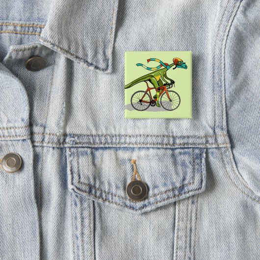 Badge Carré 5 Cm Un Dinosaure Anabisetia À Vélo. (En situation)