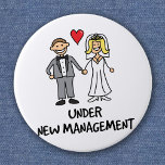 Badge Rond 5 Cm Wedding Couple - Under New Management<br><div class="desc">A cute cartoon of a newlywed couple captioned 'under new management'. Is it the bride or groom that wears the trousers in the marriage? Great for a wedding gift,  or to wear on honeymoon.</div>