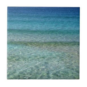 Blauw zeewater boven wit zand tegeltje