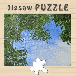 Blauwe lucht omringd door groene boombladeren Foto Legpuzzel