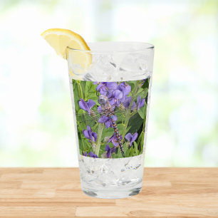 Blauwogige darner libel op paarse bloemen glas