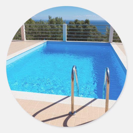 Blue swimming pool with steps at sea ronde sticker (Voorkant)