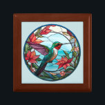 Boîte à bijoux en mosaïque de colibri Ruby Throby<br><div class="desc">Sur la couverture de cette boîte se trouve une image en mosaïque d'un colibri à gorge de rubis dans un cercle de fleurs rouges orange et de feuilles verts. Au loin se trouvent des crêtes de montagne bleues contre le ciel. L'image circulaire est bordée de bleu pâle.</div>