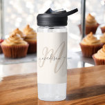 Bouteille D'eau Boho Stylish Script Monogramme et nom en beige<br><div class="desc">Une mignonne bouteille d'eau féminine avec du lettrage boho élégant avec votre initiale monogramme en gros caractères modernes en bronze neutre avec votre nom dans une police manuscrite gris fusain sur un arrière - plan beige. Le look est moderne et attrayant et tout autour de vous ! IPersonalize avec votre...</div>