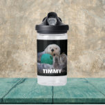 Bouteille D'eau Loutres de mer jouées avec le nom de l'enfant<br><div class="desc">La bouteille d'eau en plastique clair de taille pour enfant, avec l'image d'un couple de loutres de mer jouant avec un jouet à boule et le nom d'un enfant imprimé en lettres blanches et en gras. Personnalisez la bouteille d'eau en modifiant le nom et en la remplaçant par le nom...</div>