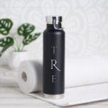 Bouteille D'eau Monogramme chic sur noir<br><div class="desc">Le chic monogramme vertical blanc sur le noir présente une initiale plus grande et plus décorative au centre. Remplacez les 3 initiales par les vôtres dans la barre latérale. Autres couleurs et styles de bouteilles d'eau disponibles dans la barre latérale. Copyright © Claire E. Skinner. Tous droits réservés.</div>