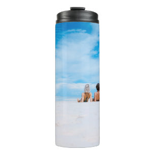 Bouteilles Isothermes Deux femmes allongées sur du sable blanc face à 