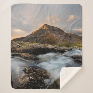 BROWN MOUNTAIN NEAR BODY OF WATER ONDER CLOUDY SKY SHERPA DEKEN