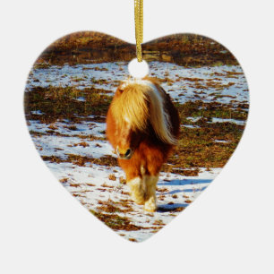 Bruin en roomminiatuur paard in de sneeuw. keramisch ornament