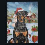 Carnet Doberman Winter Wonderland Christmas Joy<br><div class="desc">Ce design festif reflète l'esprit joyeux de la période des fêtes, avec un adorable petit portant un chapeau de Père Noël. Le chien est niché dans un pays des merveilles hivernales, avec un bonhomme de neige, un sapin de Noël décoré et des cadeaux joliment emballés. Les flocons de neige tombent...</div>