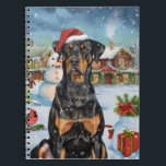 Carnet Doberman Winter Wonderland Christmas Joy<br><div class="desc">Ce design festif reflète l'esprit joyeux de la période des fêtes, avec un adorable petit portant un chapeau de Père Noël. Le chien est niché dans un pays des merveilles hivernales, avec un bonhomme de neige, un sapin de Noël décoré et des cadeaux joliment emballés. Les flocons de neige tombent...</div>