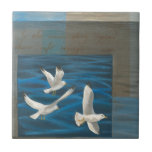 Carreau Trois mouettes blanches volent au-dessus de l'eau<br><div class="desc">Faut-il s'en aller ? Faites-le en choisissant ce tableau de l'artiste Tara Friel représentant trois mouettes volant au-dessus de l'eau. La vue des vagues de l'océan et les couleurs vives rendent ce design très réaliste.</div>