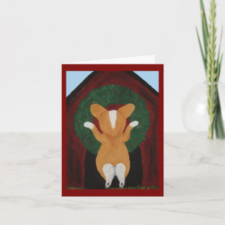 Carte Corgi posant une couronne de Noël sur une niche po