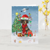 Carte Dachshund dans la neige avec des cadeaux de Noël  (Fleur jaune)