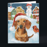 Carte Dachshund Winter Wonderland Christmas Joy<br><div class="desc">Ce design festif reflète l'esprit joyeux de la période des fêtes, avec un adorable petit portant un chapeau de Père Noël. Le chien est niché dans un pays des merveilles hivernales, avec un bonhomme de neige, un sapin de Noël décoré et des cadeaux joliment emballés. Les flocons de neige tombent...</div>