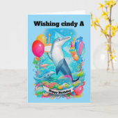 Carte Dauphin Portant un casquette d'anniversaire tenant (Fleur jaune)