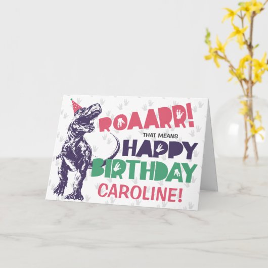 Carte Dinosaur T-Rex dans un Casquette de fête rose joye (Fleur jaune)