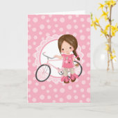 Carte Fille aux cheveux bruns à bicyclette - Rose Blanc (Fleur jaune)