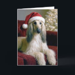 Carte La hache afghane de Noël sur un canapé en velours<br><div class="desc">Un beau chien de chien afghan avec de longs salons en fourrure soyeuse sur un canapé en velours rouge,  portant un chapeau de Père Noël festif. Le texte intérieur peut être modifié.</div>
