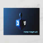 Carte Postale Dreidel bleu brillant<br><div class="desc">Un rêve moderniste bleu métallique contre un arrière - plan sombre et nocturne. Deux des lettres hébraïques trouvées sur un dreidel,  une nonne et un shin,  brillent brillamment. Le texte hébreu "Chag Chanukkah Sameach" (Hanoukka heureuse) apparaît également en bleu et blanc éclatant.</div>