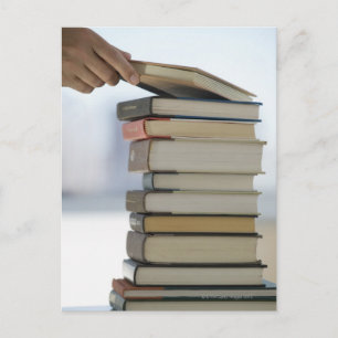 Carte Postale La main de l'homme prenant un livre d'une pile de