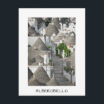 Carte Postale Rue avec trulli maisons à Alberobello, Pouilles<br><div class="desc">Carte postale d'une rue vide bordée de trulli traditionnels en plâtre blanc avec toits en forme de cône en début de matinée dans la ville italienne du sud Alberobello dans les Pouilles,  Italie avec une frontière blanche et le texte "Alberobello".</div>