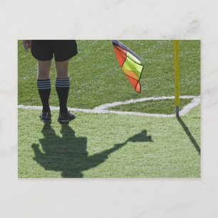 Carte Postale Un arbitre de football tient le drapeau.