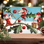 Carte postale Vintage Christmas Elves Holly Holida<br><div class="desc">Carte postale Vintage Christmas Elves Holly Holiday. Belle carte postale vintage elfe de Noël. Ce design présente des elfes mignons peignant des feuilles saints et des baies. Quelle belle scène de vacances.</div>