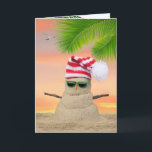 Carte Tropical Christmas Sand Snowman<br><div class="desc">Tropical "bonhomme de neige" dans le sable avec casquette à rayures et lunettes de soleil sur le sable avec ciel couché de soleil.</div>