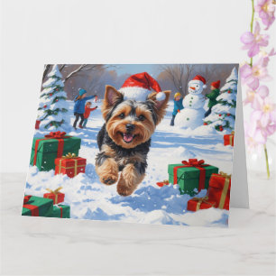 Carte Yorkipoo courant dans la neige avec un chapeau de