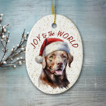 Chocolat Labrador Retriever Dog Joy au monde<br><div class="desc">Sur le devant de cet ornement de vacances est une belle image d'un chien de Labrador Retriever brun chocolat dans un casquette du Père Noël. Derrière l'image se trouve un arrière - plan à confettis doré. Le texte rouge dit "Joy to the World". Le dos de l'ornement a le même...</div>
