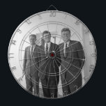 Cible De Fléchettes Le président John Kennedy et les frères American C<br><div class="desc">Le soleil frappa les trois frères Kennedy alors qu'ils se tenaient sous le portique blanc familier de la Maison Blanche. Le président John F. Kennedy, l'aîné, s'appuyait sur un pilier, un sourire irréfléchi jouant sur ses lèvres. Ses frères plus jeunes, Robert et Ted, se tenaient à ses côtés, et leurs...</div>