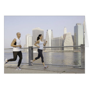 Couple courant sur la jetée avec la ville en arriè