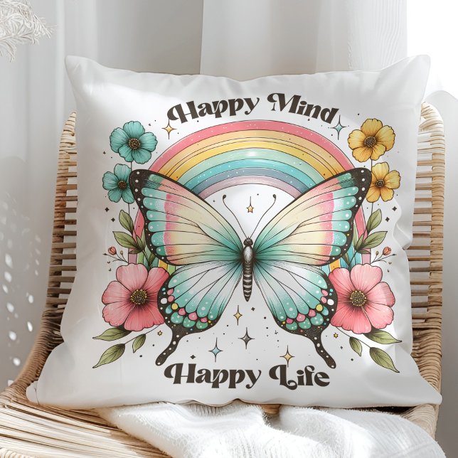 Coussin "Esprit Heureux Vie Heureuse" Papillon Pastel Arc- ("Happy Mind Happy Life" Pastel Butterfly Rainbow Throw Pillow in a sunny rattan armchair.)