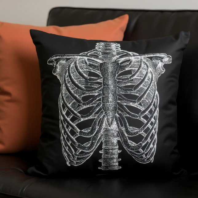 Coussin Illustration d'anatomie ancienne - Torse de squele (A black pillow with a skeleton in front on a couch with another pillow.)