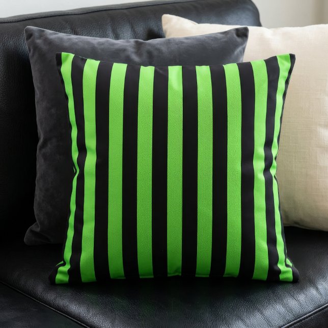 Coussin Motif rayures vert lime et noir (A lime green and black stripes pillow sits on a black couch in front of other pillows.)