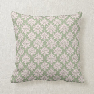 Coussin rose pâle sur fond de vert sauge avec un motif orn