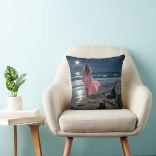 Coussin Sorcière portant une robe rose sur une plage au cl