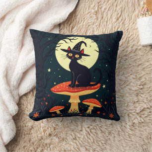 Coussin Une petite chatte noire de sorcière assise sur un