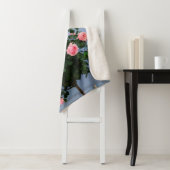 Couverture Sherpa Fleurs rouges avec feuilles verts sur mur bleu (En situation)