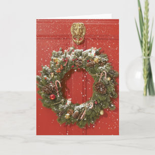 De kroon van Kerstmis het hangen op een deur Feestdagen Kaart