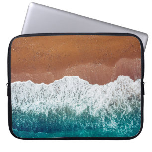 De oceaangolf op een zandstrand, uitzicht bovenaan laptop sleeve