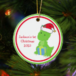 Décoration En Céramique 1er Noël du bébé Dinosaur personnalisé mignon<br><div class="desc">Customisez ce joli ornement de Noël de bébé dinosaure avec le nom de votre enfant ou un autre texte à l'intérieur du cercle vert et rouge. Des enfants personnalisées ornent avec un dino dans un casquette du Père Noël en vacances.</div>
