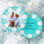 Décoration En Céramique Sable de sable de la plage de Noël Dollar de l'éto<br><div class="desc">Une couronne de dollars de sable blanc, d'étoiles de mer et de corail de parties scintillant d'aqua encadrent la photo de famille sur le devant de cet ornement à thème de plage, avec un arrière - plan bleu aqua, avec le nom de famille, l'année, et Joyeux Noël sur le dos....</div>