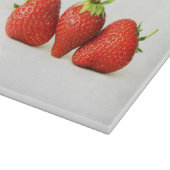 Drie aardbeien op witte cbcnm snijplank (Hoek)