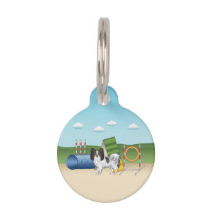 Driekleurige Papillon-hond met agilityapparatuur Huisdierpenning