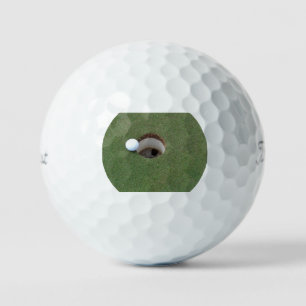 Dwaas die op de rand van het gat zit. golfballen